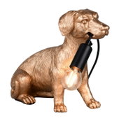 Tischleuchte in Form eines sitzenden Hundes aus goldfarbenem Material, der eine Glühbirne im Maul hält. Seitliche Perspektive.