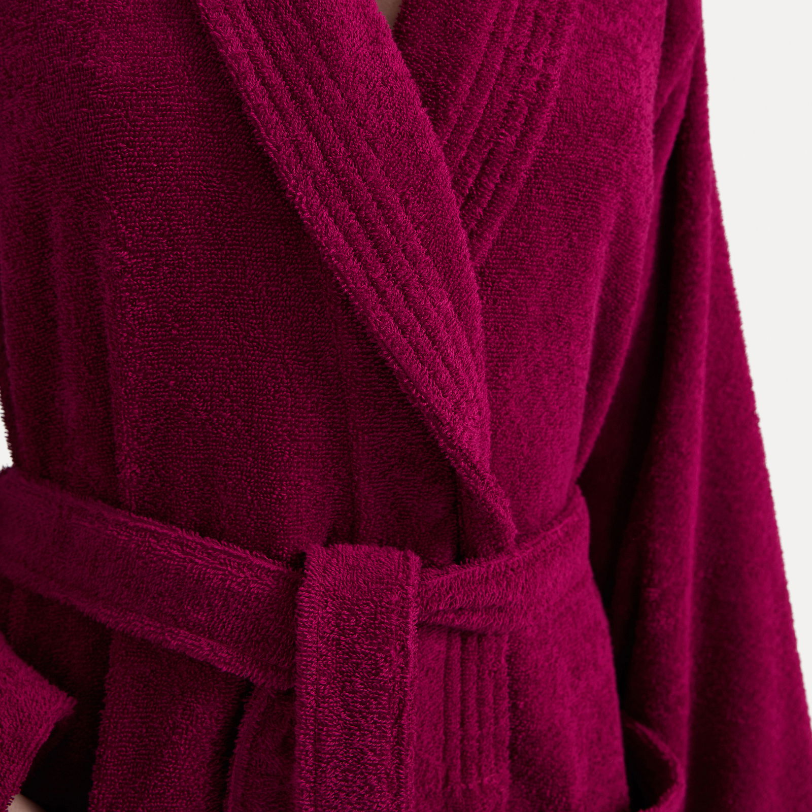 Nahaufnahme eines weinroten Bademantels mit Schalkragen und Gürtel.