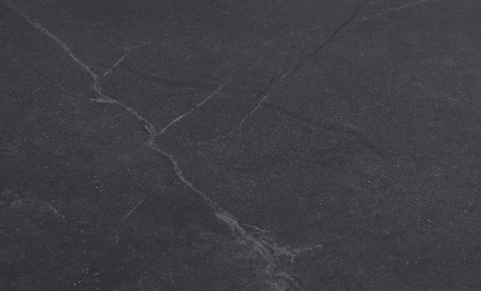Draufsicht auf eine dunkle, marmorierte Tischplatte mit feinen, hellen Adern.