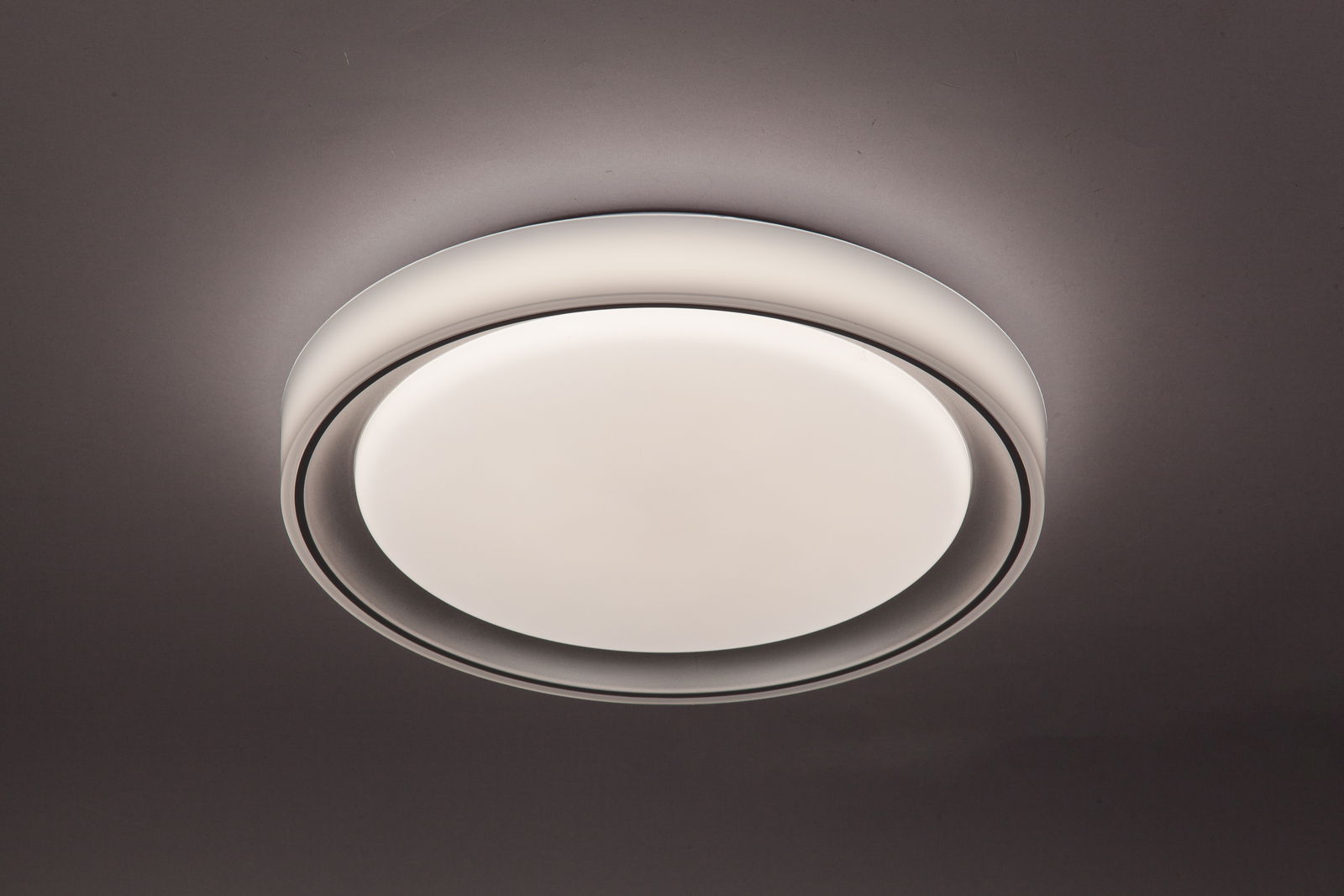 Runde LED-Deckenleuchte in moderner Optik, von unten betrachtet, mit sanftem Lichtschein an der Decke.