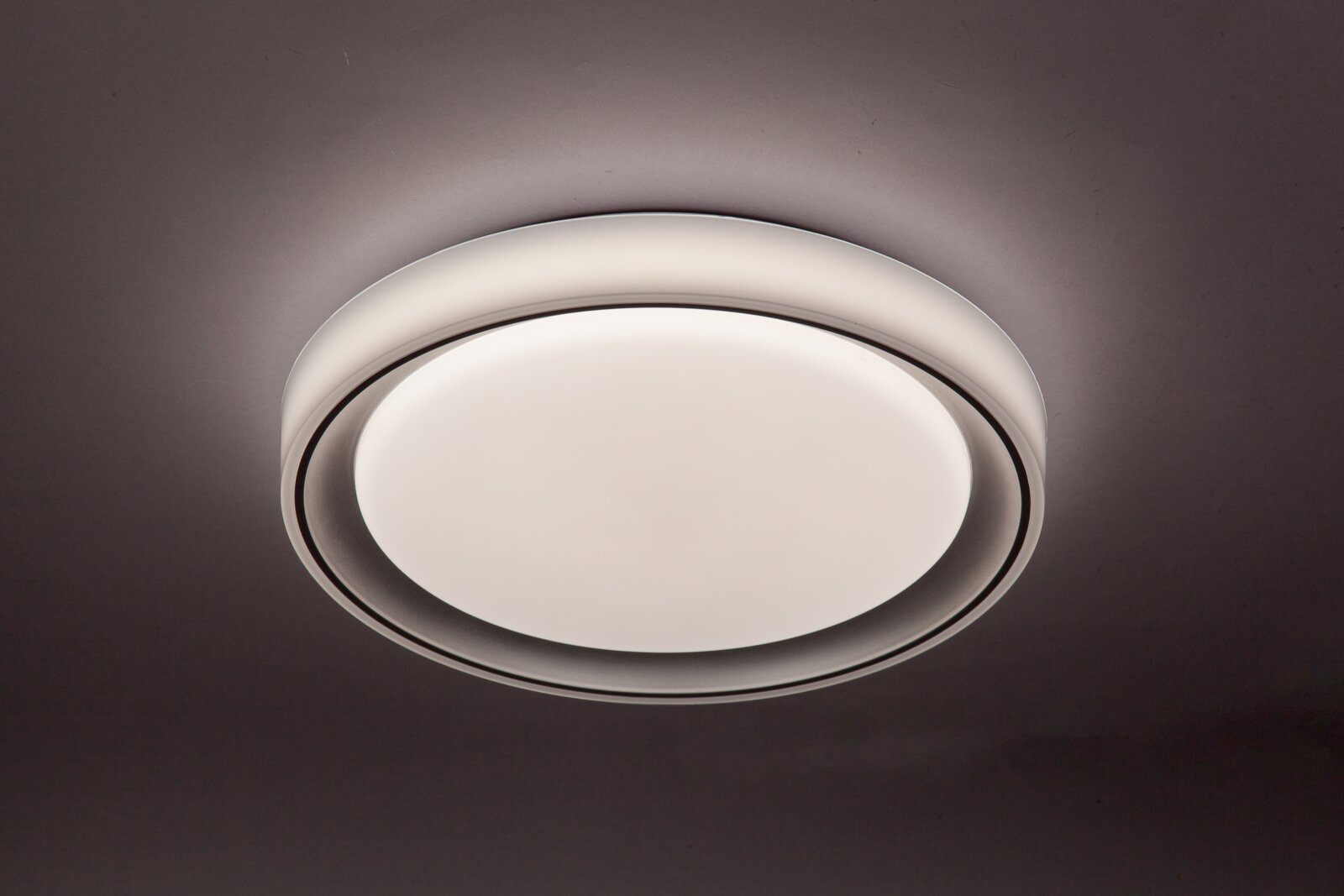Runde LED-Deckenleuchte in moderner Optik, von unten betrachtet, mit sanftem Lichtschein an der Decke.