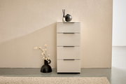 Schmaler, moderner Schubladenschrank in Creme/Beige mit vier Schubladen und schwarzen Griffleisten, frontal aus Augenhöhe vor einer strukturierten Wand fotografiert; oben Deko mit Duftdiffusor und schwarzer Vase, daneben schwarze Bodenvase mit Blüten.