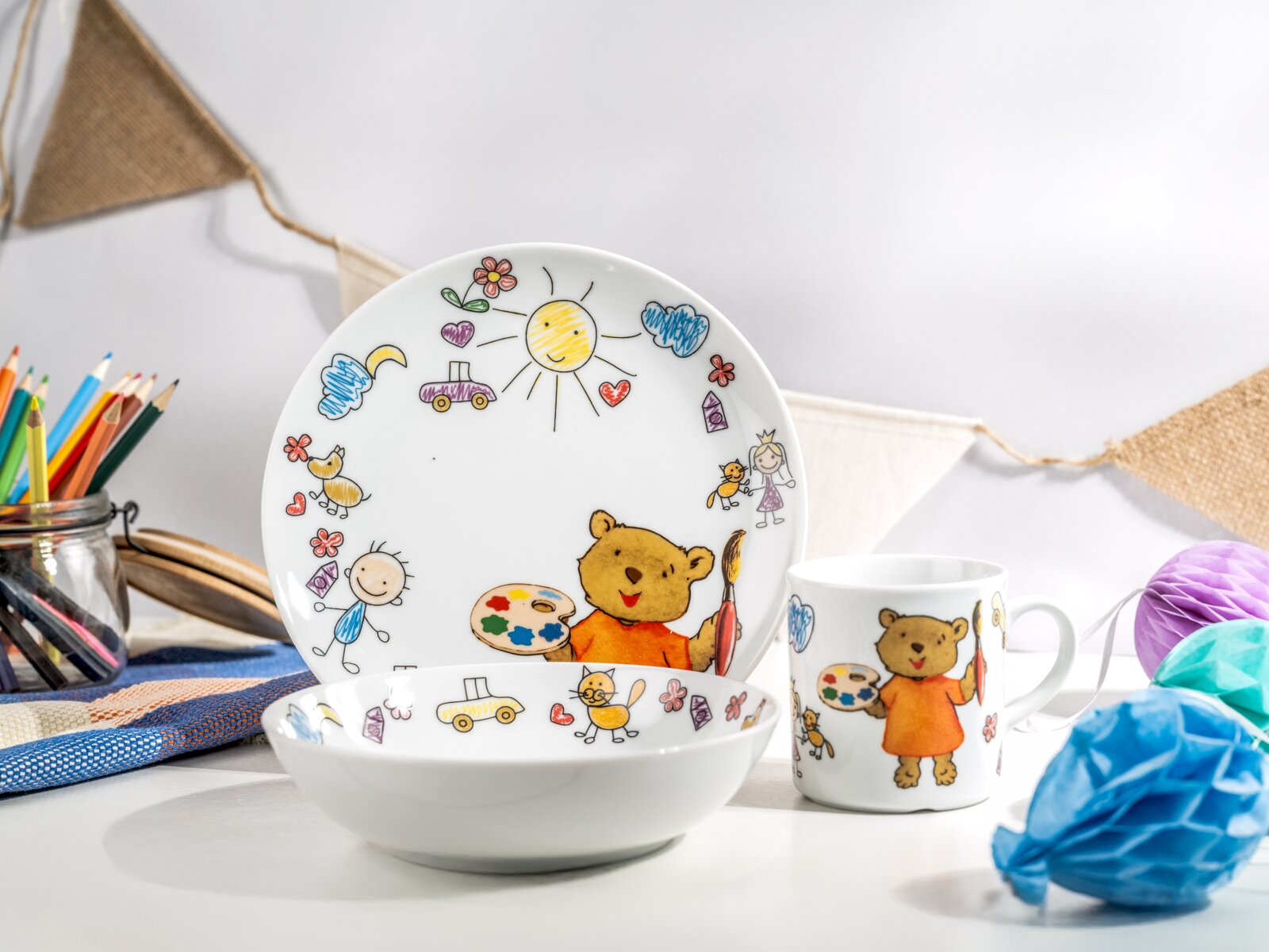 Creatable Kinderservice 3-tlg TEDDY Kinder-Geschirrset aus weißem Porzellan mit Teller, Schale und Tasse, bunt illustriert mit Bär und kindlichen Zeichnungen; aufgenommen in leicht schräger Frontansicht auf weißem Hintergrund