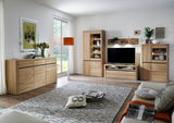 Modernes Wohnzimmer mit einem Sideboard aus Holz, das links im Raum steht. Die Perspektive zeigt das Sideboard von vorne, umgeben von stilvoller Dekoration und einem großen Fenster im Hintergrund.