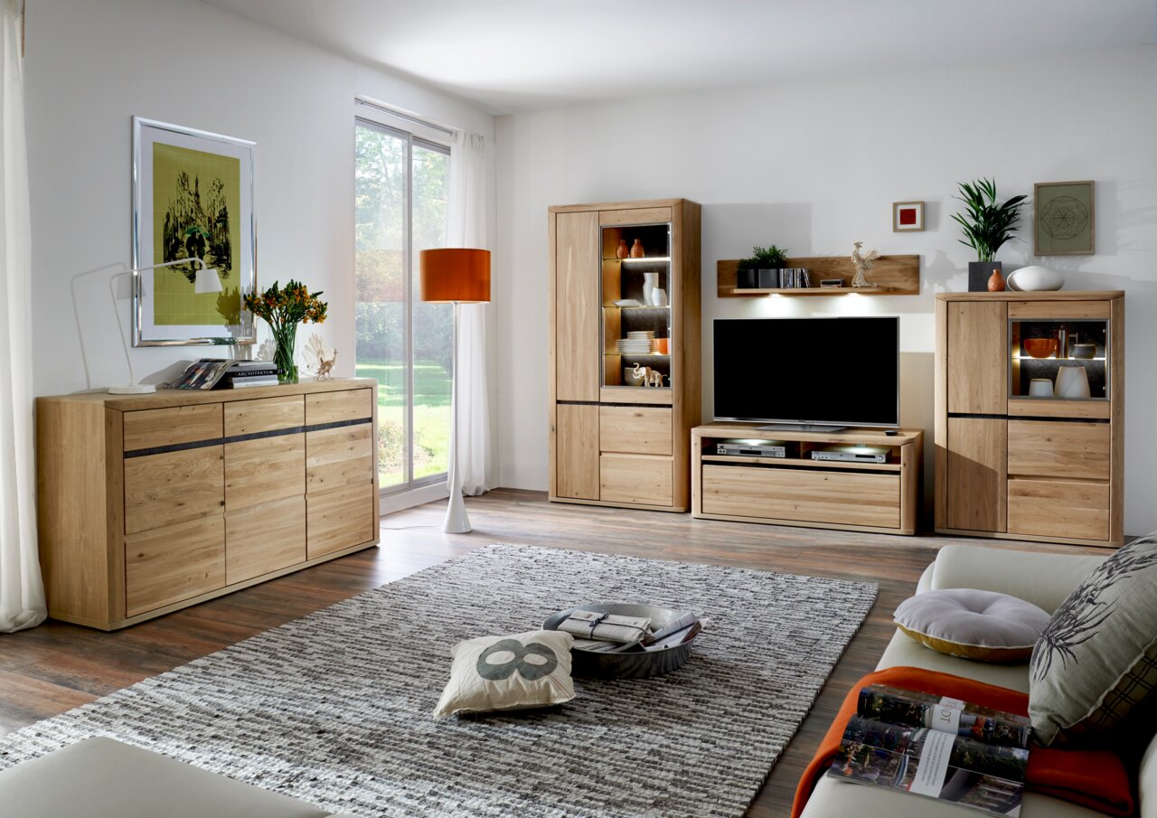 Een moderne woonkamer met een houten dressoir dat links in de kamer staat. Het perspectief toont het dressoir van voren, omringd door stijlvolle decoratie en een groot raam op de achtergrond.