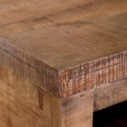 Close-up van een hoek van een rustiek houten nachtkastje, gezien van bovenaf.