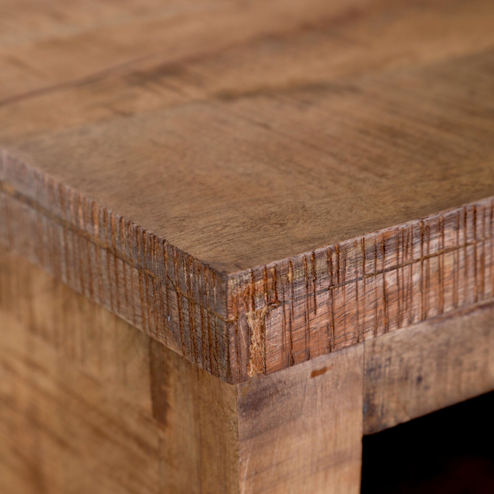 Close-up van een hoek van een rustiek houten nachtkastje, gezien van bovenaf.