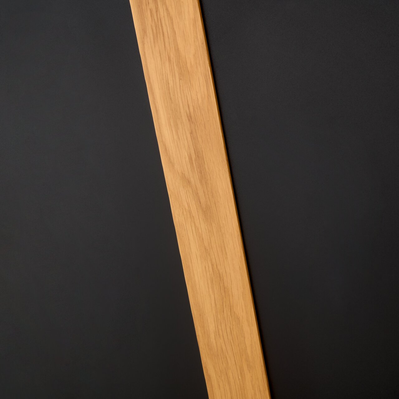 Nahaufnahme eines Esstischs mit einer Holzplatte und schwarzer Oberfläche, diagonale Perspektive.