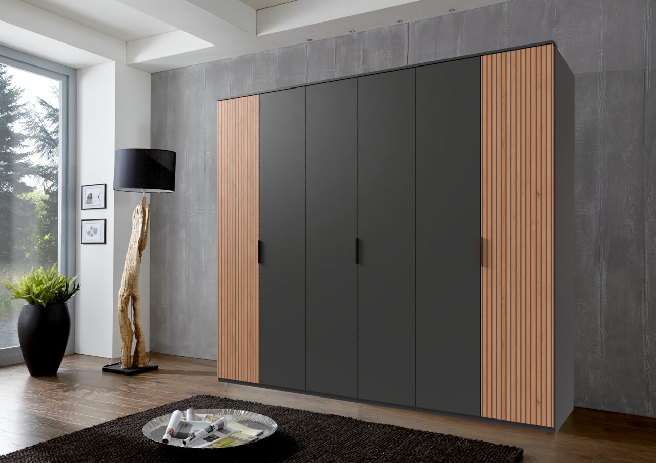 Moderne kast met zes draaideuren in zwart met houten details, gefotografeerd van voren in een stijlvol ingerichte ruimte.