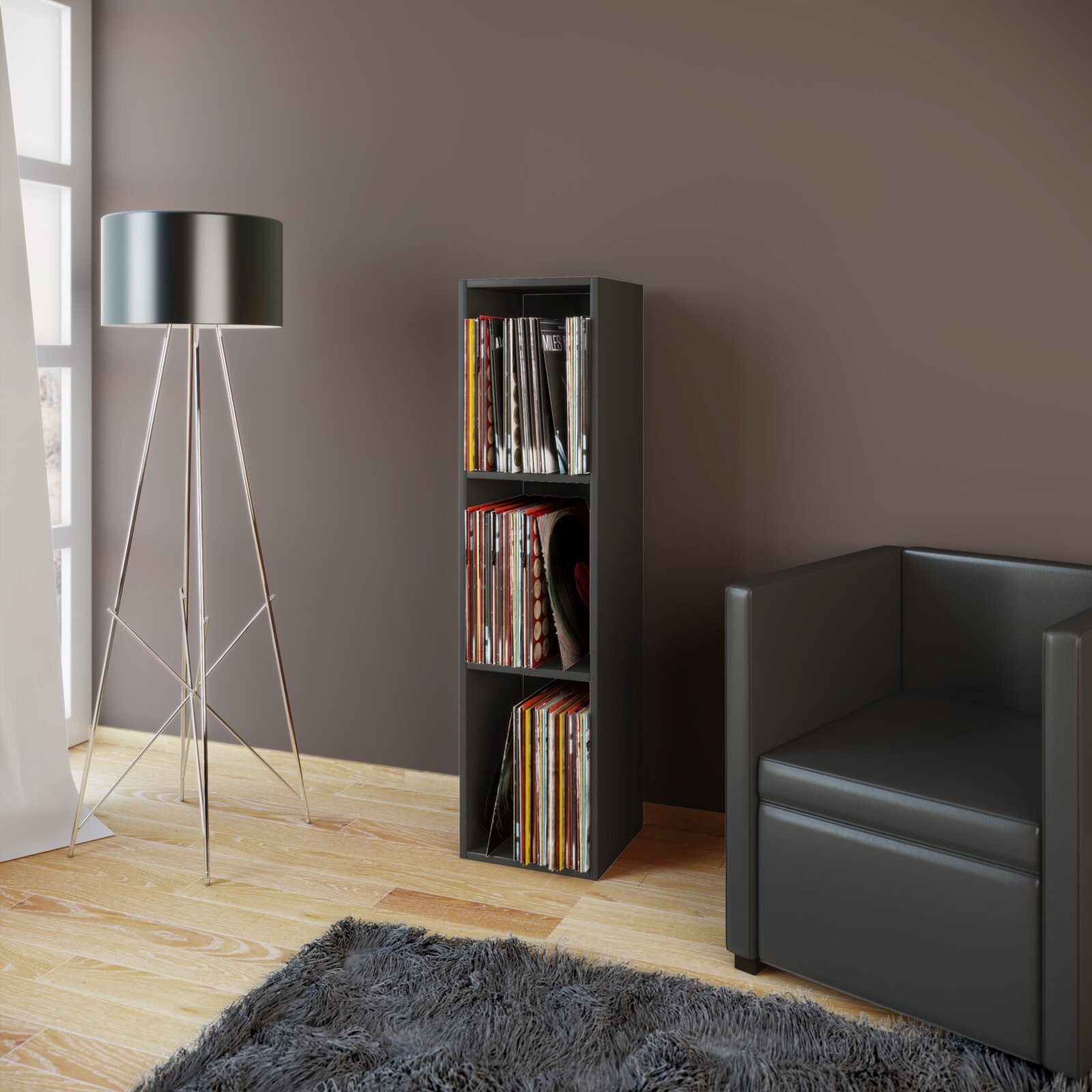 Schmales schwarzes Vinyl-Schallplattenregal mit drei Fächern, gefüllt mit LPs, im Wohnzimmer neben schwarzem Sofa und Stehlampe, frontale Perspektive leicht von links