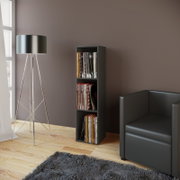 Schmales schwarzes Vinyl-Schallplattenregal mit drei Fächern, gefüllt mit LPs, im Wohnzimmer neben schwarzem Sofa und Stehlampe, frontale Perspektive leicht von links