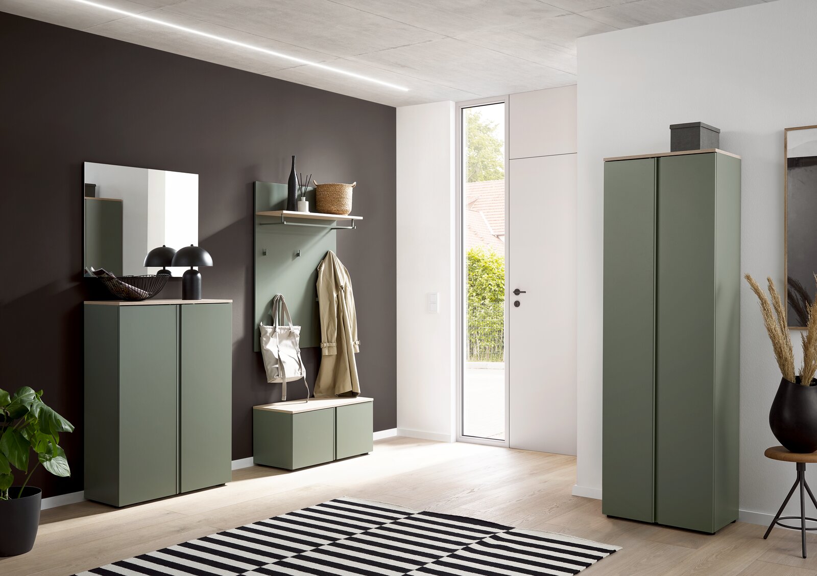 Voleo Bank MILTON Modernes Flur-Set in Salbeigrün mit Garderobenpaneel, Sitzbank und zwei Schränken, fotografiert in frontaler Perspektive mit leichtem Weitwinkel in einem hellen Eingangsbereich.