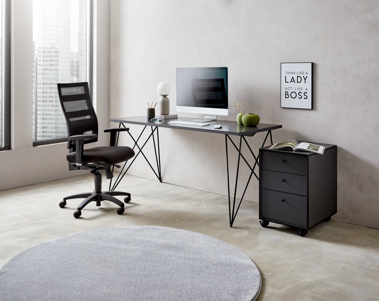 Moderner Schreibtisch mit schwarzem Metallgestell, Computer und Dekorationen, seitliche Perspektive