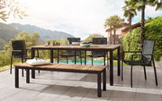 Moderner Gartensessel aus Metall und Holz, Teil einer stilvollen Terrassenmöbelgruppe mit Blick auf einen Pool und eine malerische Berglandschaft.