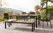 Moderner Gartensessel aus Metall und Holz, Teil einer stilvollen Terrassenmöbelgruppe mit Blick auf einen Pool und eine malerische Berglandschaft.