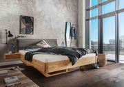 Massivholzbettgestell in modernem Schlafzimmer, seitliche Perspektive mit großem Fenster im Hintergrund.