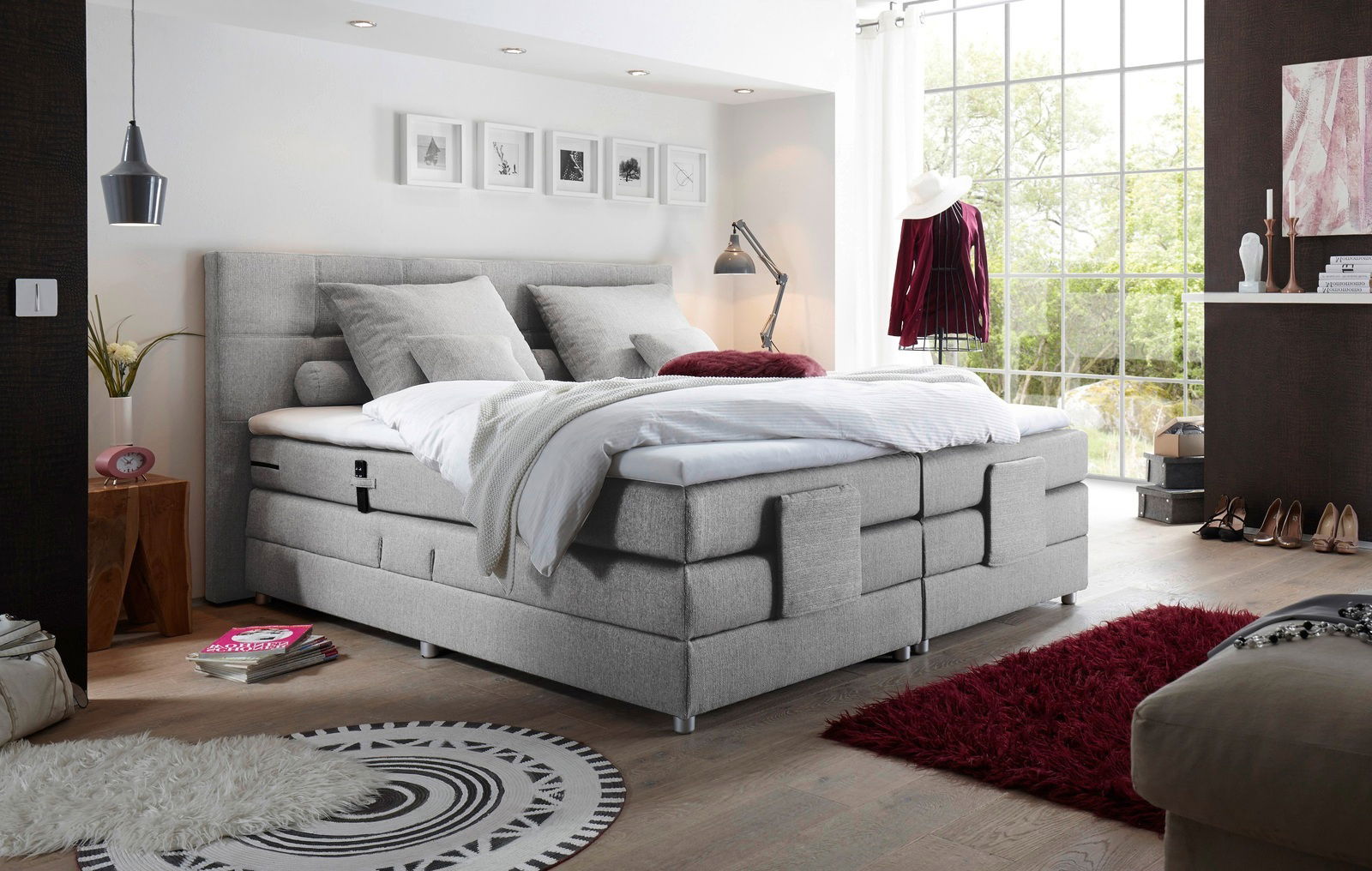 Modernes graues Boxspringbett in einem stilvoll eingerichteten Schlafzimmer mit Blick aus der Ecke des Raumes.