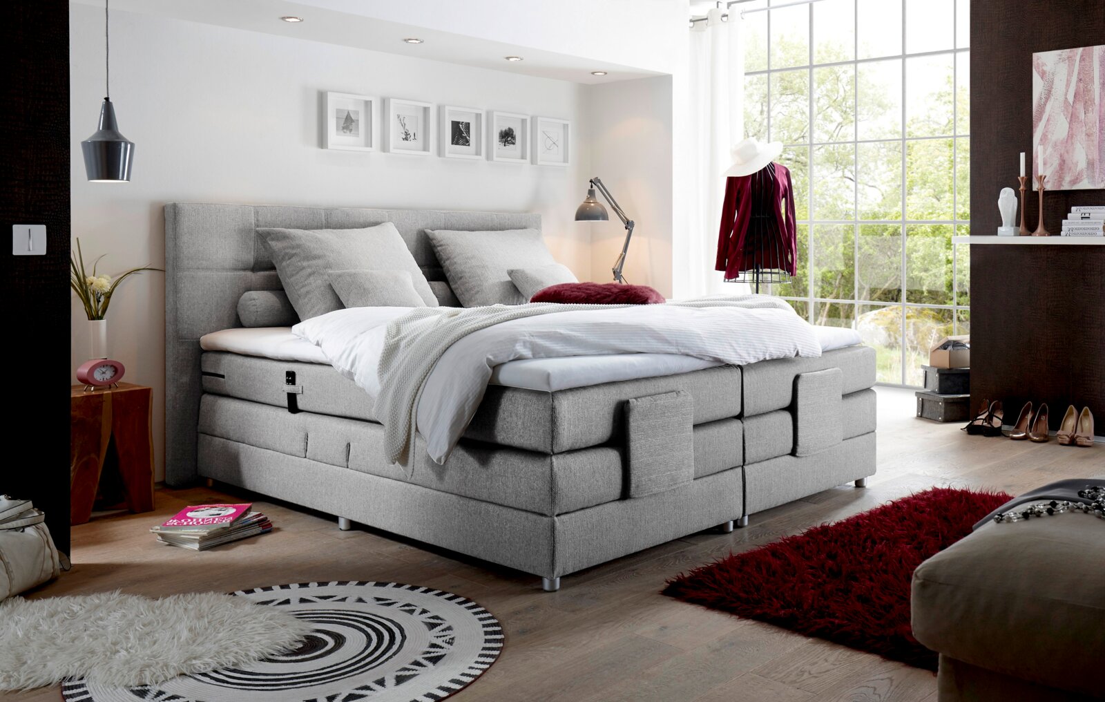 Modernes graues Boxspringbett in einem stilvoll eingerichteten Schlafzimmer mit Blick aus der Ecke des Raumes.