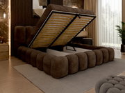 Een gestoffeerd bed in een moderne slaapkamer, gezien vanaf de zijkant, met het matras omhoog geklapt en opbergruimte eronder.