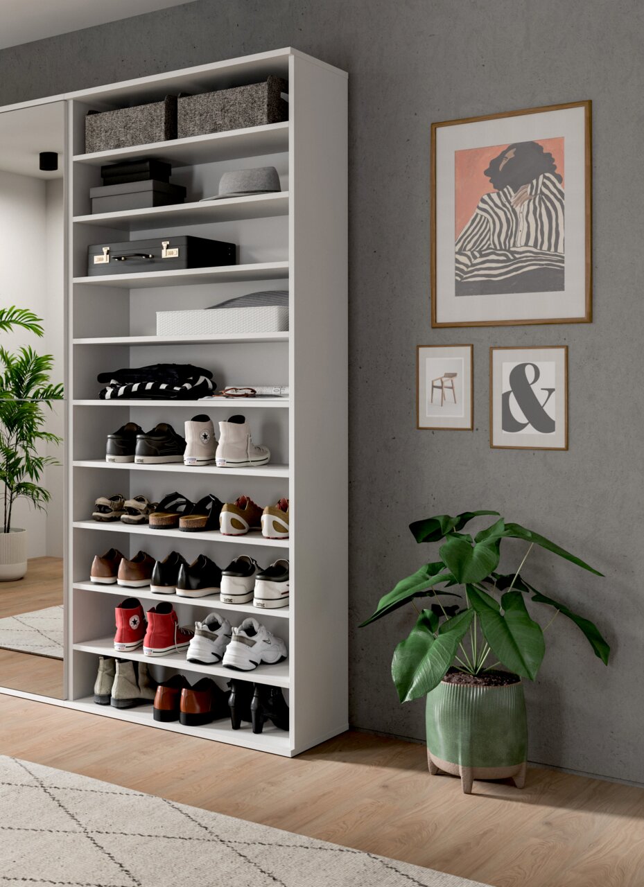 Weißes Schuhregal mit mehreren Fächern, gefüllt mit verschiedenen Schuhen und Accessoires, in einem modernen Raum mit Pflanzen und Wanddekorationen. Perspektive von vorne links.