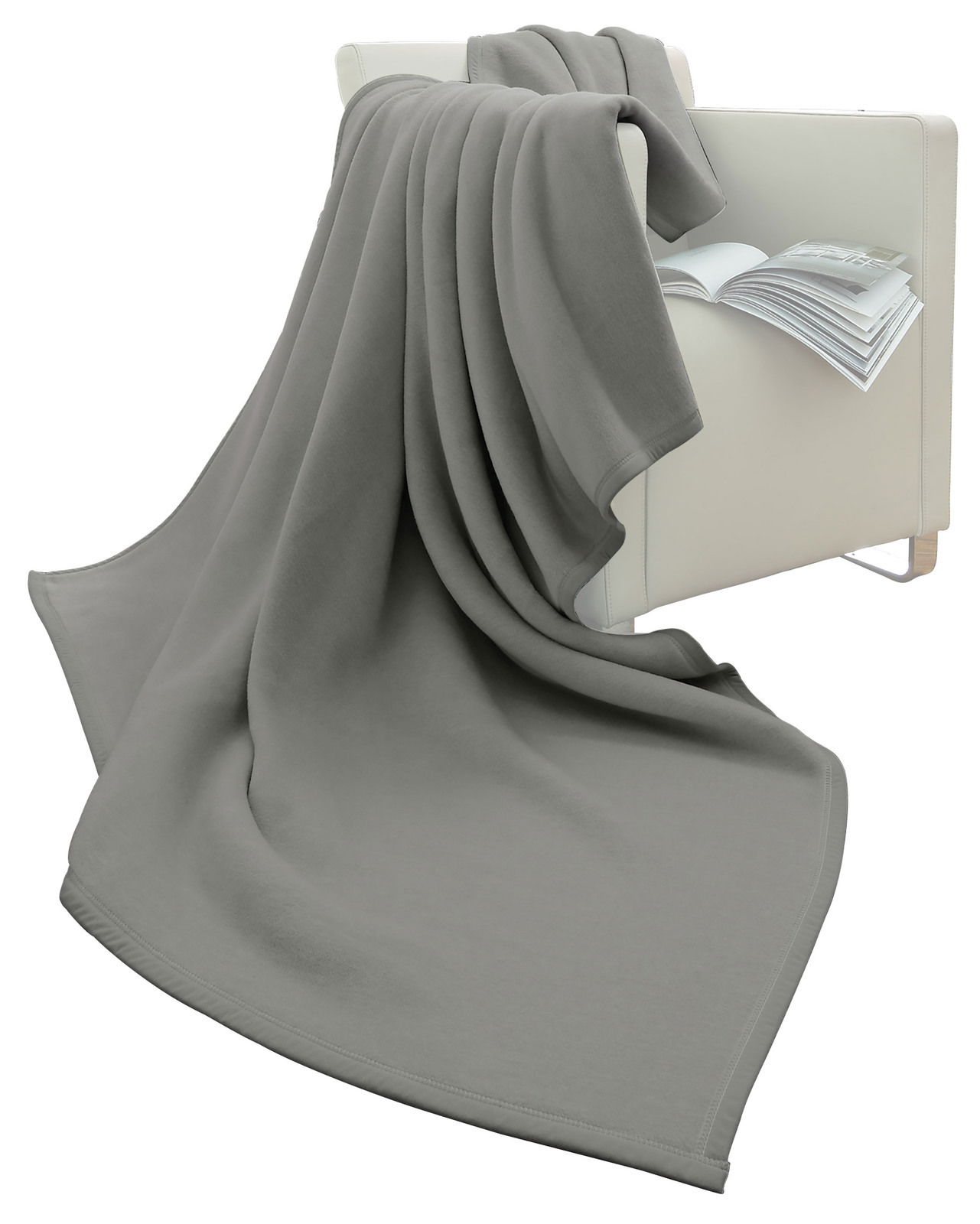 Graue Wohndecke 150 x 200 cm, drapiert über einen weißen Sessel mit einem offenen Buch, seitliche Perspektive