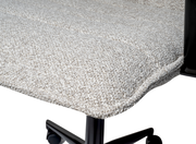 Nahaufnahme eines gepolsterten Drehstuhlsitzes mit hellgrauem Stoffbezug und schwarzem Metallgestell, seitliche Perspektive.