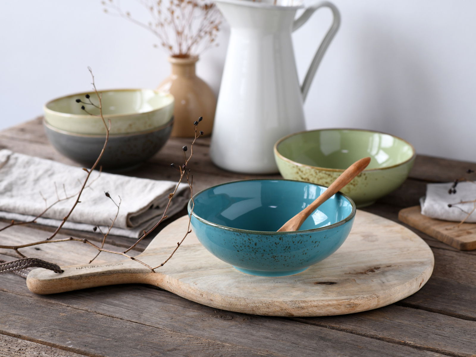 Vogelperspektive auf ein Set aus vier Smoothie-Schalen in verschiedenen Farben, arrangiert auf einem rustikalen Holztisch mit dekorativen Elementen.