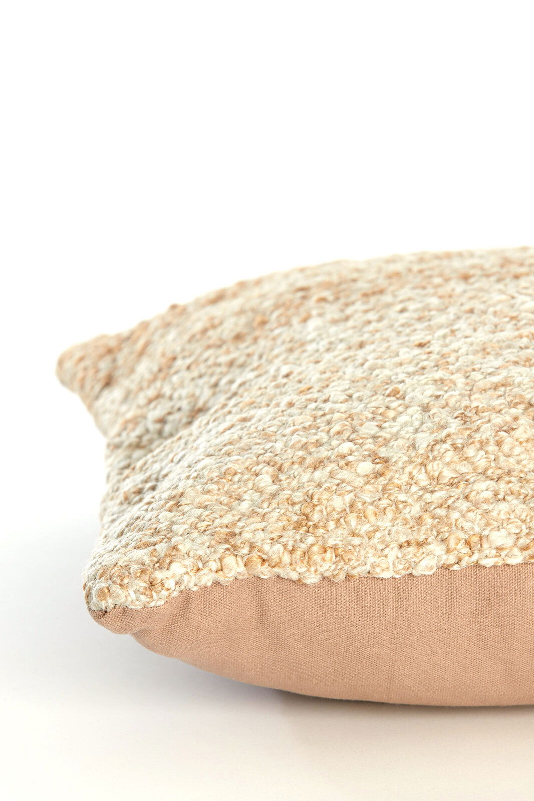 Nahaufnahme eines Kissens mit strukturierter, cremefarbener Oberfläche und glatter, beiger Unterseite, seitliche Perspektive