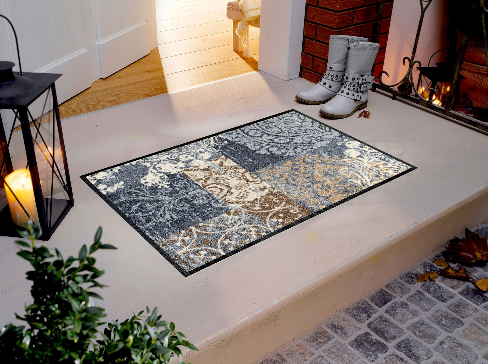 Fußmatte mit floralem Muster in Grau- und Brauntönen auf einer Veranda, seitliche Perspektive