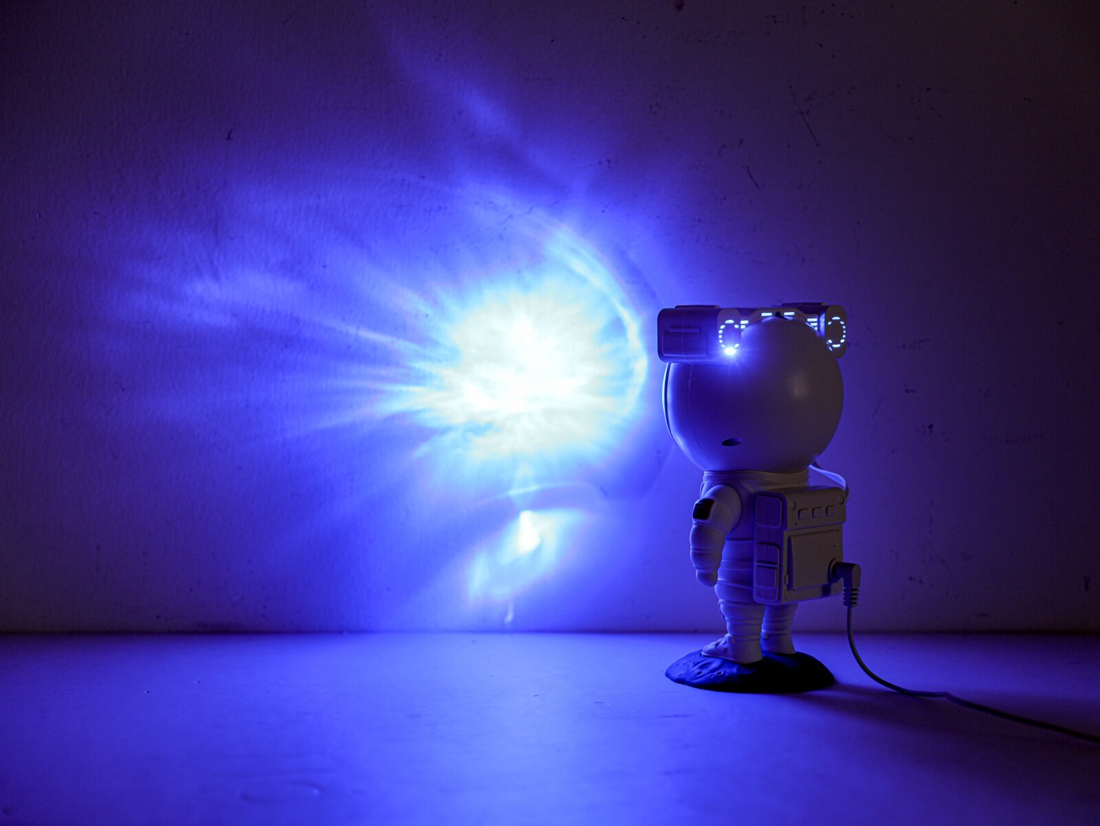 LED-Dekoleuchte in Form eines Astronauten, der blaues Licht an die Wand projiziert, seitliche Perspektive