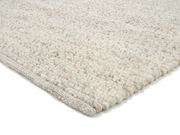 Nahaufnahme eines handgewebten Teppichs in hellen Naturtönen, seitliche Perspektive