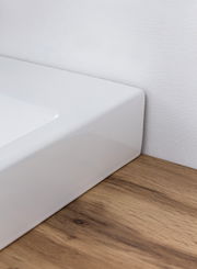 Nahaufnahme eines weißen Waschtischs auf einer Holzoberfläche, seitliche Perspektive