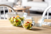 Ein 5-teiliges Schalenset aus Glas, bestehend aus verschiedenen Größen, präsentiert auf einem Tisch. Die Schalen sind teilweise mit frischem Salat gefüllt. Perspektive: seitlich von vorne.