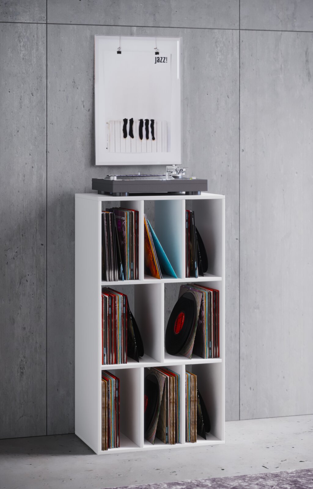 VCM LP-Regal SCHALTINO Weißes, schmales Schallplattenregal mit 6 Fächern, gefüllt mit Vinylplatten; oben steht ein Plattenspieler, im Hintergrund ein gerahmtes Poster an einer Betonwand – frontale Ansicht auf das Produkt.