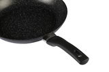 Nahaufnahme einer schwarzen Bratpfanne mit gesprenkelter Antihaftbeschichtung und ergonomischem Griff, seitliche Perspektive.