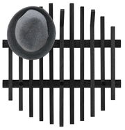 Schwarzes Garderobenpaneel aus Holz mit vertikalen und horizontalen Streben, darauf ein grauer Hut, Ansicht von oben.