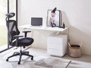 Moderner Schreibtisch mit weißer Oberfläche, seitlich betrachtet, ausgestattet mit einem Laptop, Schreibtischlampe, Dekoration und einem ergonomischen Bürostuhl.