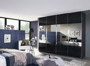 Moderner Schwebetürenschrank mit schwarzer Hochglanzoberfläche und Spiegeln, seitliche Perspektive im stilvollen Schlafzimmer.