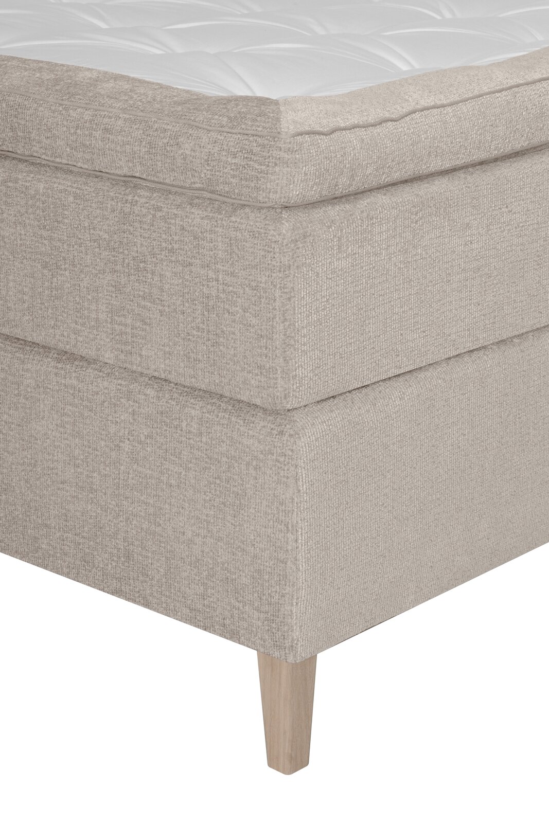 Nahaufnahme eines Boxspringbettes in Beige mit Holzfuß, seitliche Perspektive
