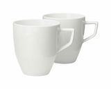 Zwei weiße Becher mit Henkel, im Set, aus seitlicher Perspektive fotografiert.