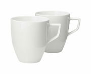 Zwei weiße Becher mit Henkel, im Set, aus seitlicher Perspektive fotografiert.