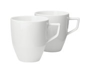Zwei weiße Becher mit Henkel, im Set, aus seitlicher Perspektive fotografiert.