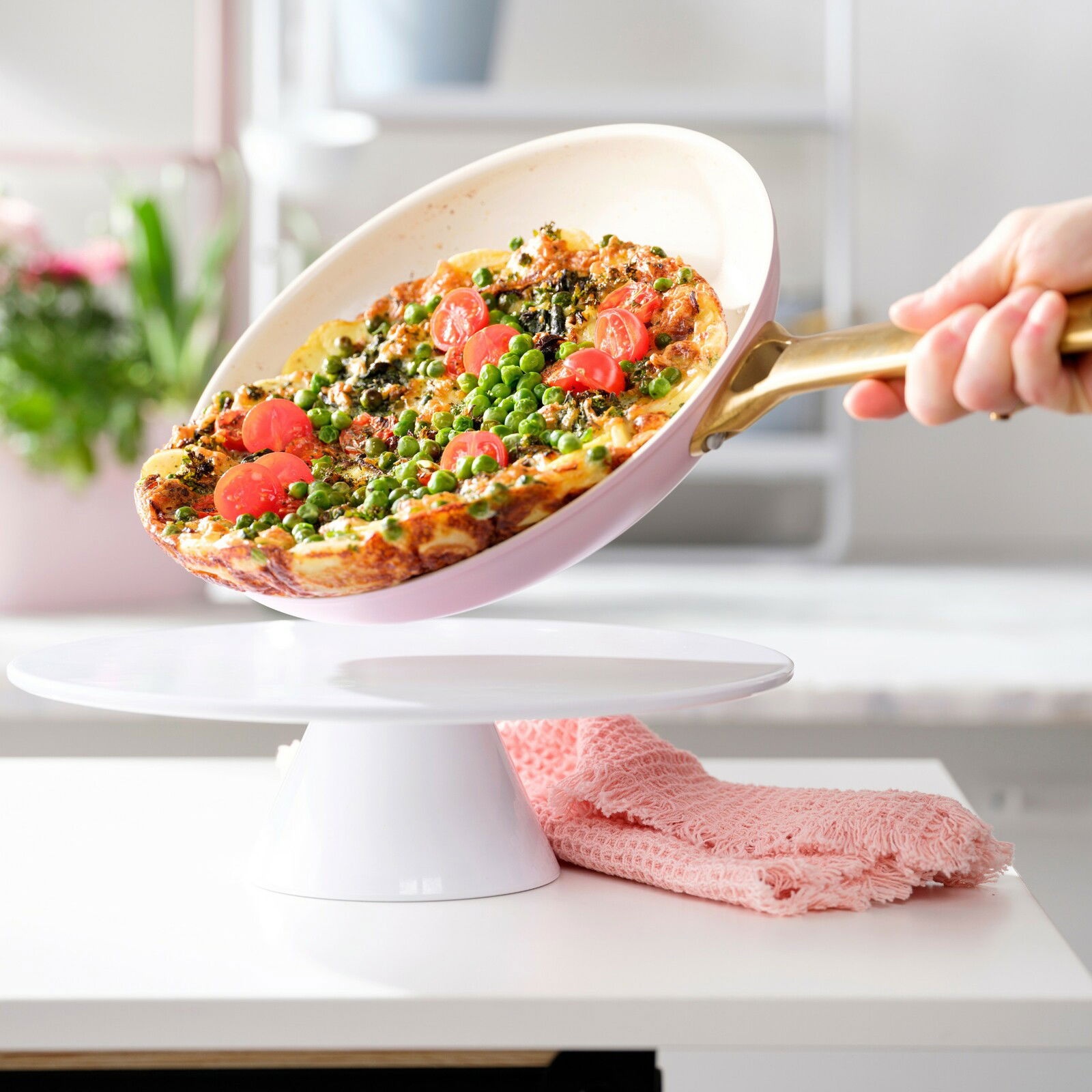 Bratpfanne mit goldfarbenem Griff, in der eine bunte Gemüse-Frittata serviert wird, seitliche Perspektive