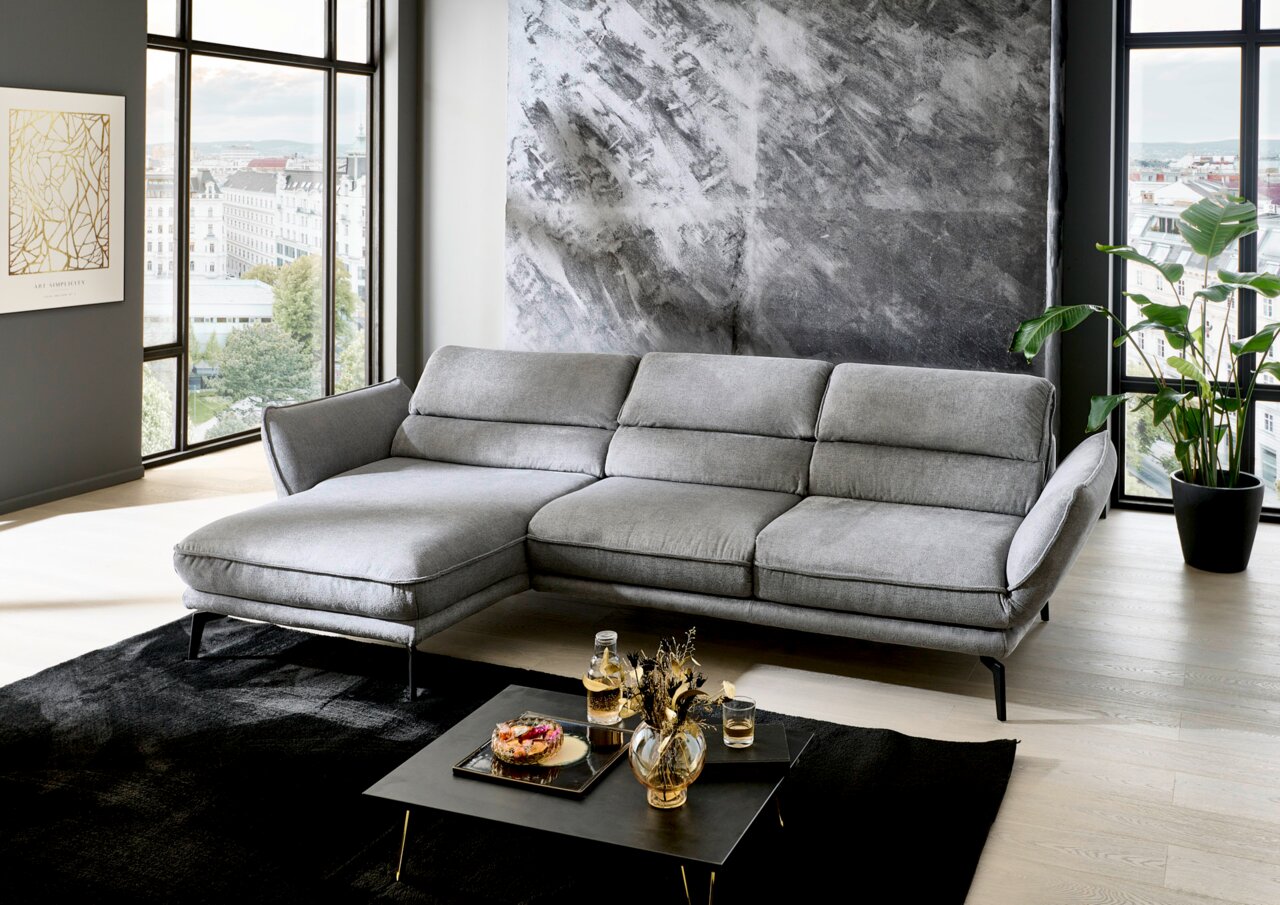 Grijze longchair-set in een moderne woonkamer met grote ramen en een stijlvolle inrichting, zijaanzicht