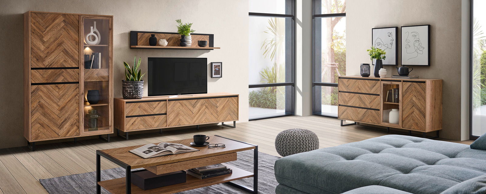 Wohnzimmer mit modernem Möbelset aus Holz in Fischgrätmuster, bestehend aus Vitrine, TV-Lowboard, Couchtisch und Sideboard, seitliche Perspektive