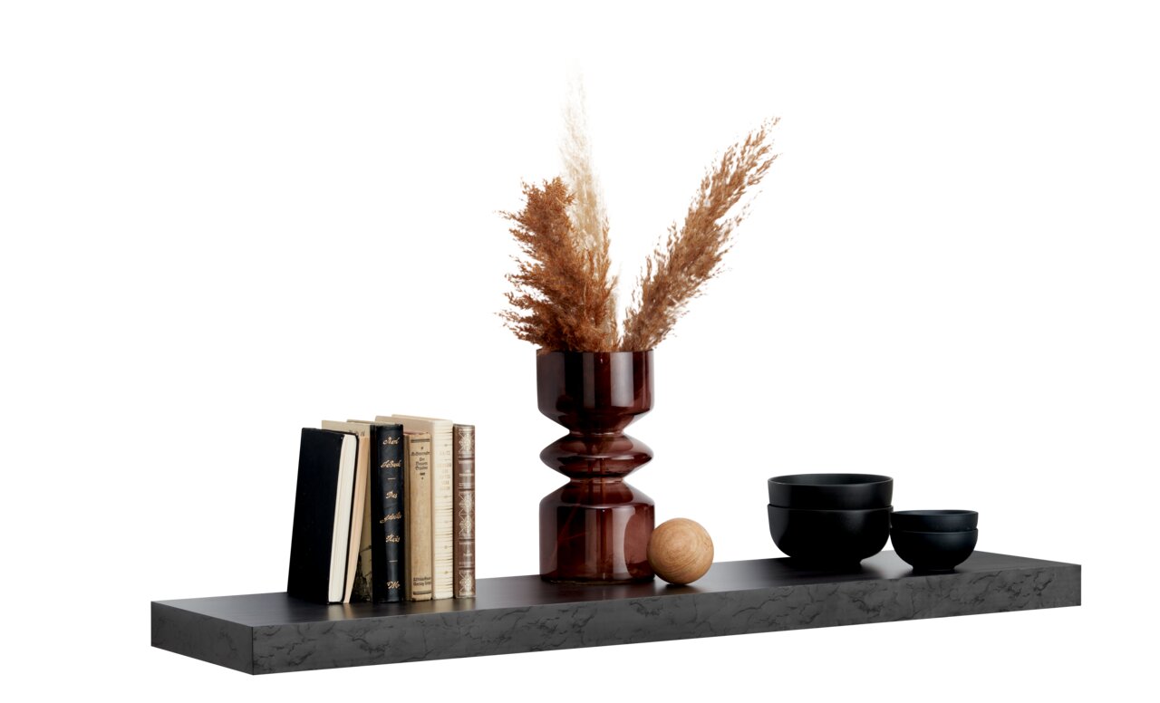 Wandboard mit Dekoration, darunter Bücher, eine Vase mit Pampasgras und schwarze Schalen, seitliche Perspektive