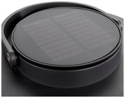 Nahaufnahme einer runden Solarlampe mit schwarzem Gehäuse und sichtbarem Solarpanel von oben.