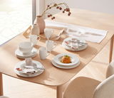 Kombiservice Basic White 20-teilig auf einem Holztisch, von oben fotografiert, mit Tellern, Tassen und Schalen in schlichtem Weiß.