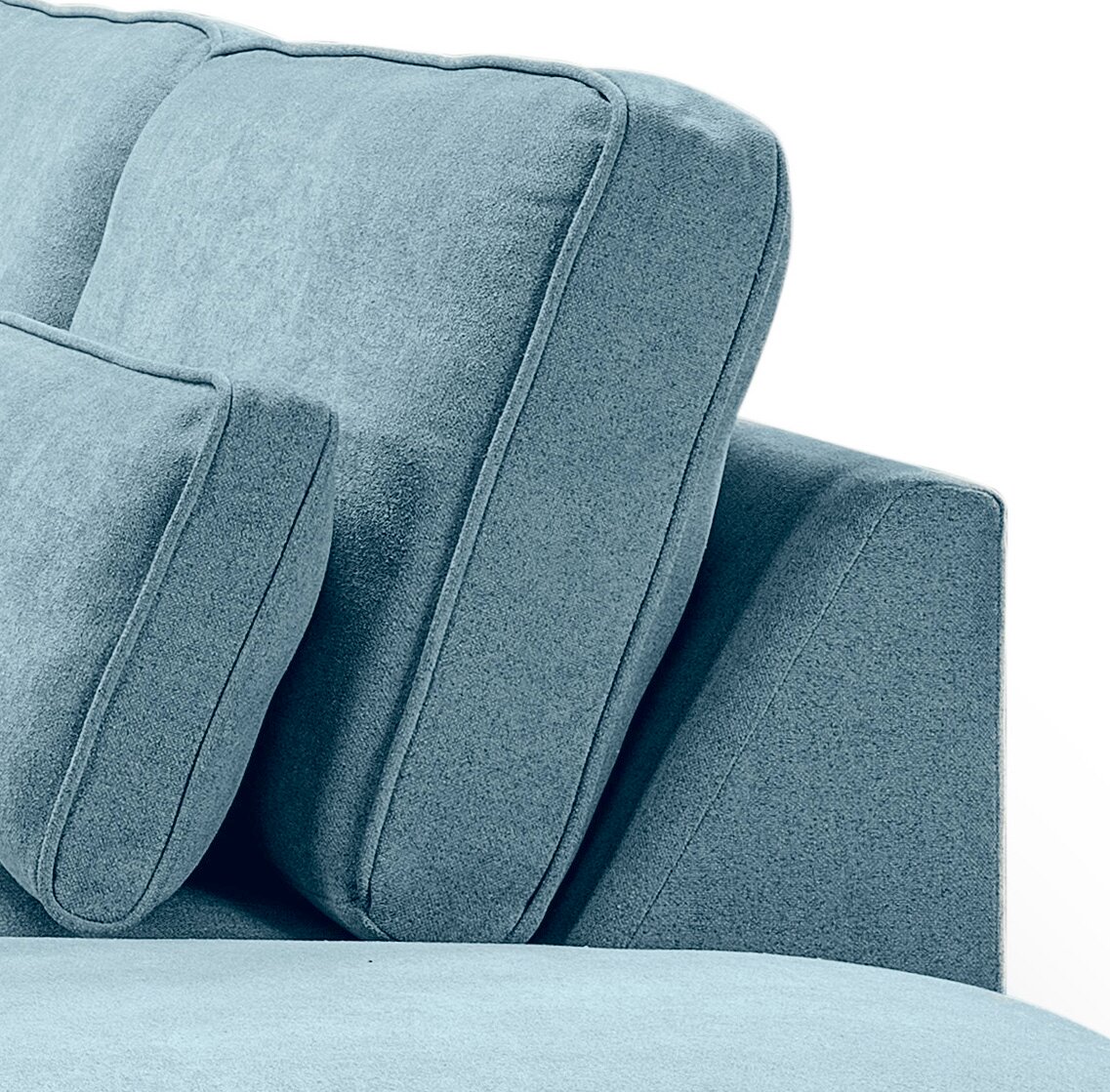 Nahaufnahme eines hellblauen, gepolsterten Sofas mit weichem Stoffbezug, sichtbaren Nähten und Kissen, seitliche Perspektive
