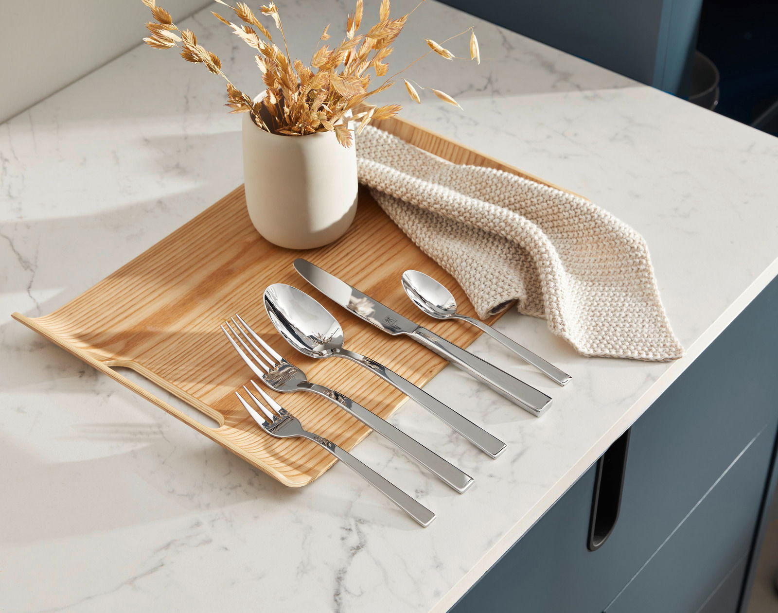 Elegantes Besteckset King 30-tlg. auf einem Holztablett, von oben fotografiert, mit dekorativer Vase und Stoffserviette.